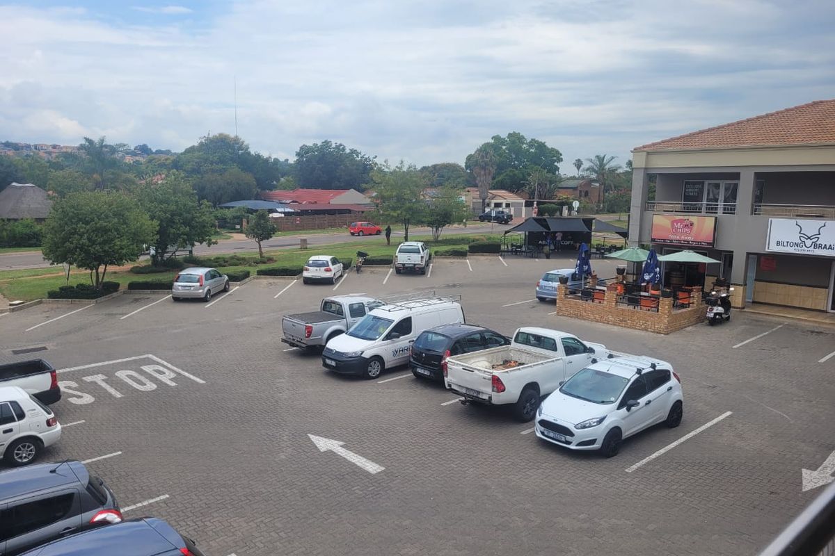 An elevated view of a commercial retail property featuring a paved parking lot and an outdoor seating area adjacent to the building.