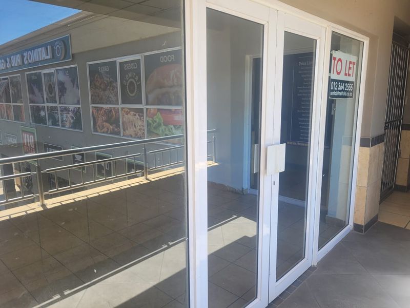 Front entrance of a retail unit featuring glass double doors, tiled flooring, and a stainless steel balustrade overlooking the exterior area.