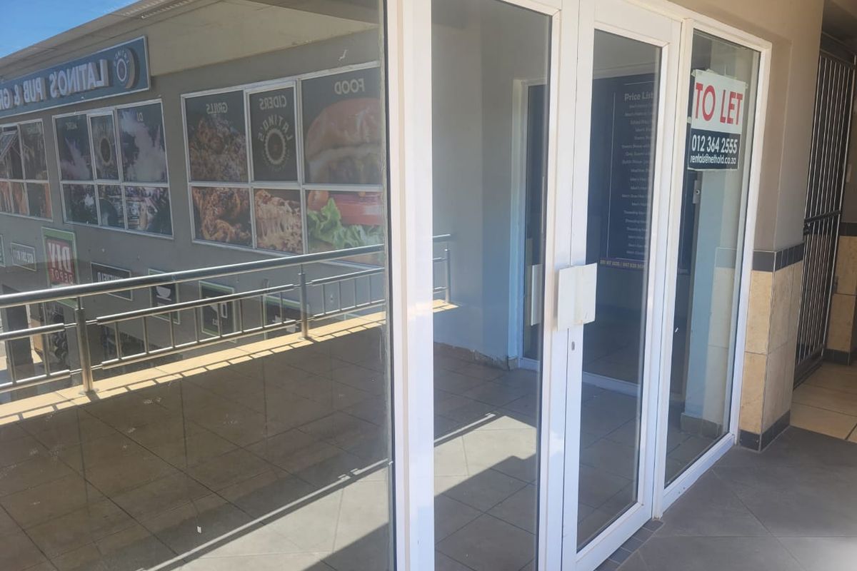Front entrance of a retail unit featuring glass double doors, tiled flooring, and a stainless steel balustrade overlooking the exterior area.