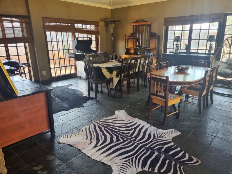 Spacious dining area featuring dark slate tile flooring, large sliding glass doors providing natural light, and traditional timber window frames.