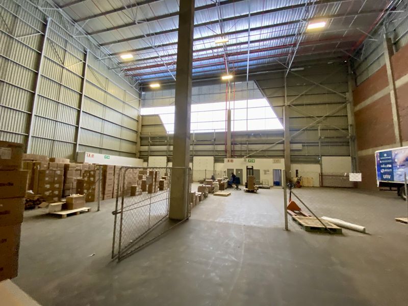 Spacious industrial warehouse featuring high ceilings, concrete flooring, steel portal frame construction, and integrated fire sprinkler systems, suitable for storage or manufacturing operations.