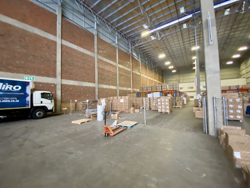 Spacious industrial warehouse featuring high ceilings, exposed brick walls, concrete flooring, and high bay lighting, suitable for storage or distribution operations.