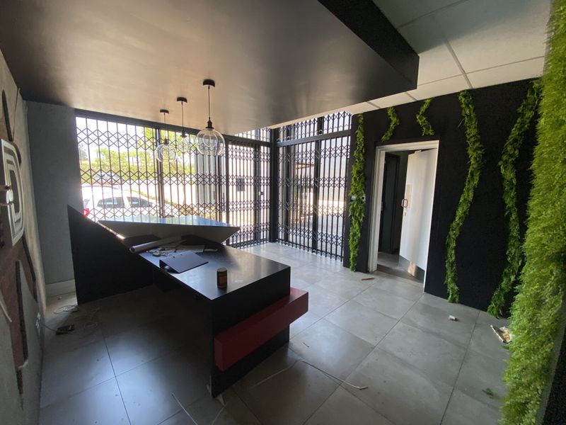 Modern industrial-style reception area featuring a built-in desk, tiled flooring, security gates, and decorative wall accents.