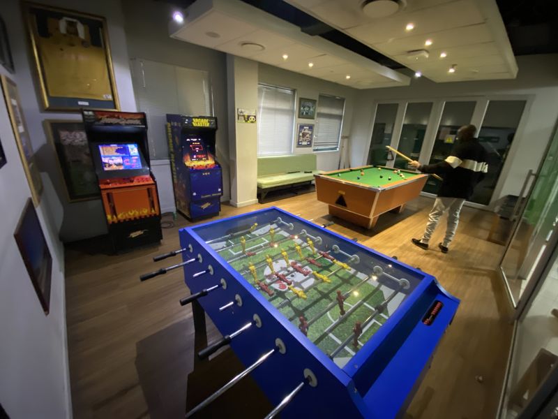 A well-maintained industrial clubhouse or recreational space featuring laminate flooring, recessed lighting, and large sliding glass doors.