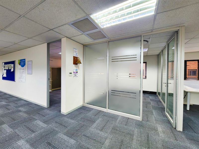 A professional office space featuring modular carpet tiles, suspended ceilings with recessed lighting, and frosted glass partitions creating a clean, functional work environment.