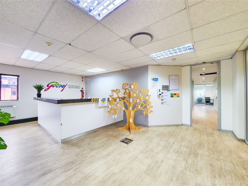 Professional office reception area featuring a built-in reception desk, wood-look laminate flooring, and a suspended ceiling with integrated lighting.