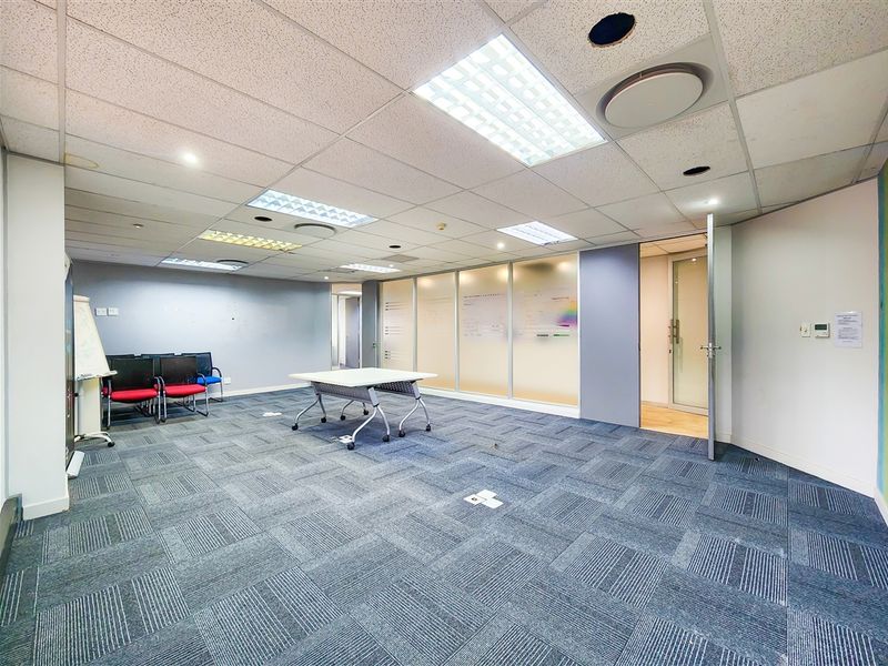 A functional office space featuring carpet tiles, a suspended ceiling with recessed lighting, and a glass partition wall for a professional work environment.