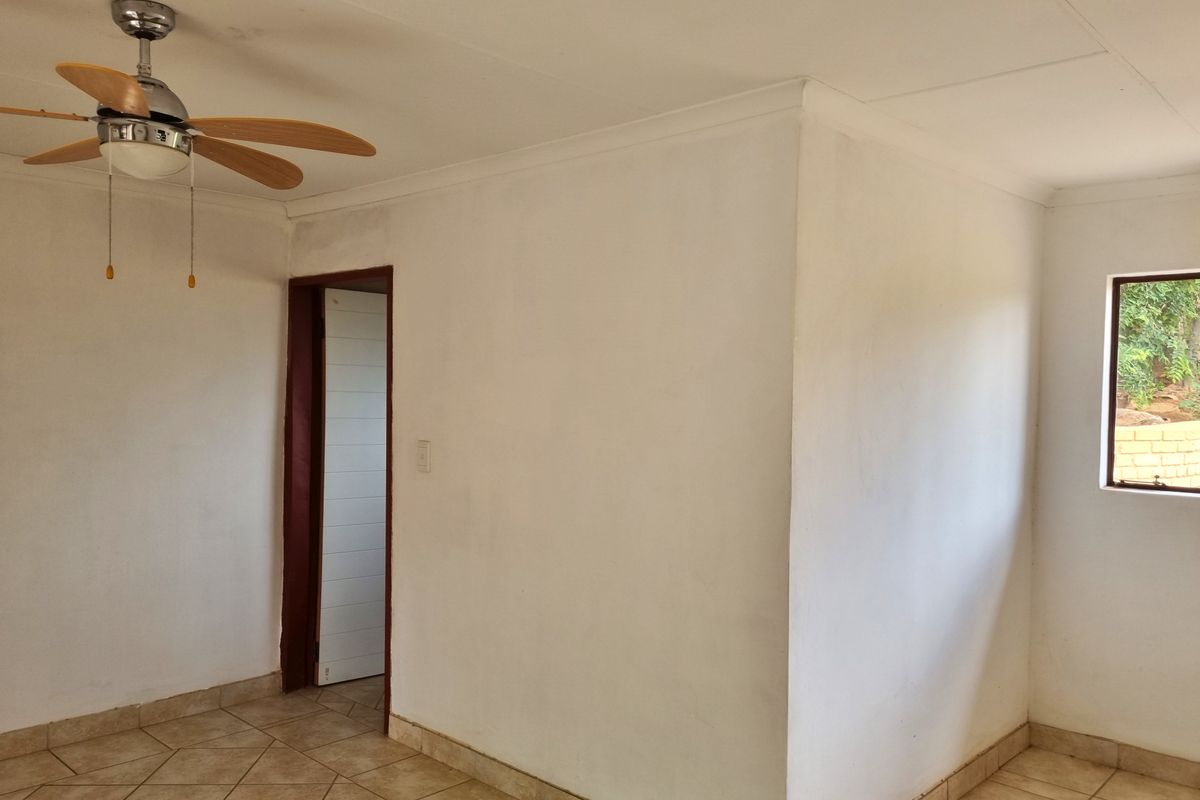 A vacant bedroom featuring tiled flooring, a ceiling fan, and neutral walls, offering a blank canvas for interior design and personalization.