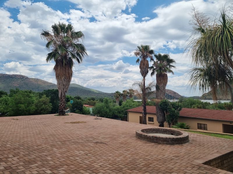 Spacious outdoor patio area featuring brick paving and a built-in circular brick fire pit, offering scenic views of the surrounding landscape and mountains.