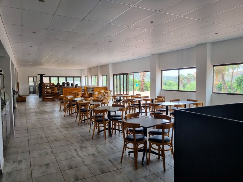 Spacious open-plan dining area featuring tiled flooring, suspended ceilings, and large windows providing natural light and scenic views.