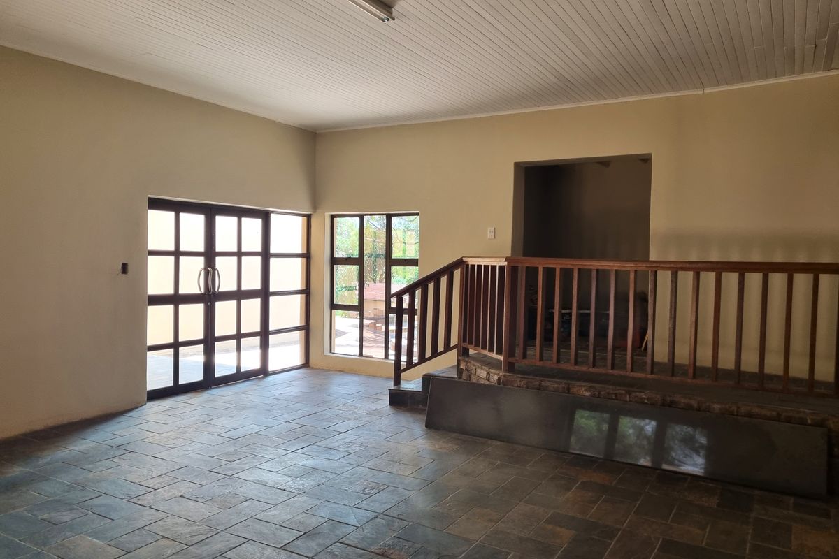Spacious living area featuring slate tile flooring, a timber balustrade, and large glass doors leading to the exterior.