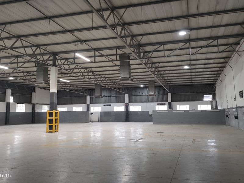 Spacious industrial warehouse unit featuring high ceilings with exposed steel trusses, concrete flooring, industrial lighting, and integrated ventilation systems.