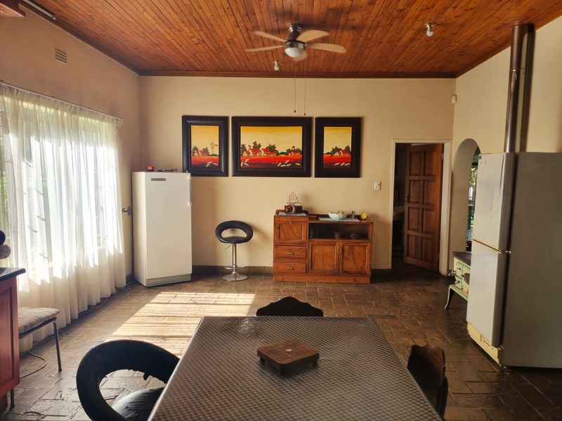 Open plan living and dining area featuring rustic stone tile flooring, a warm timber ceiling, and a traditional wood-burning stove.