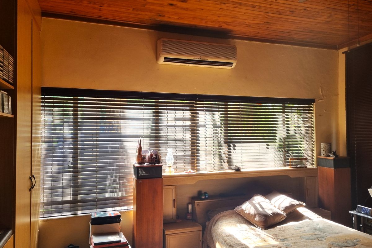 Bedroom featuring a timber ceiling, built-in cabinetry with integrated headboard, and a wall-mounted air conditioning unit.