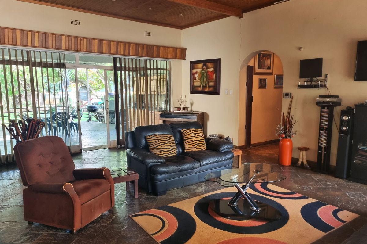 Spacious living room featuring stone tile flooring, a timber-clad ceiling, and large sliding glass doors providing direct access to the outdoor patio area.