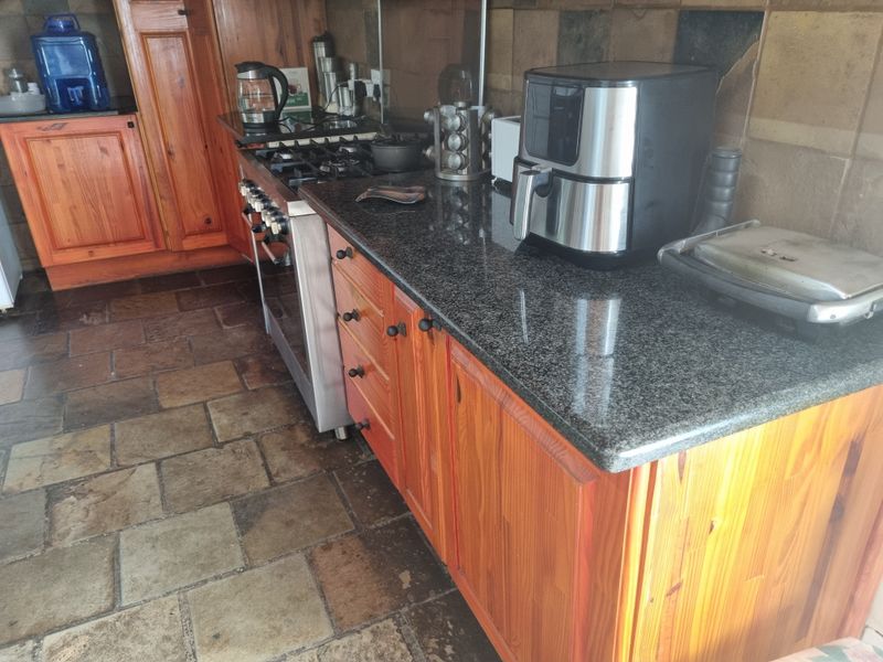 Kitchen featuring wooden cabinetry, granite countertops, gas stove, and stone tile flooring with a tiled backsplash.