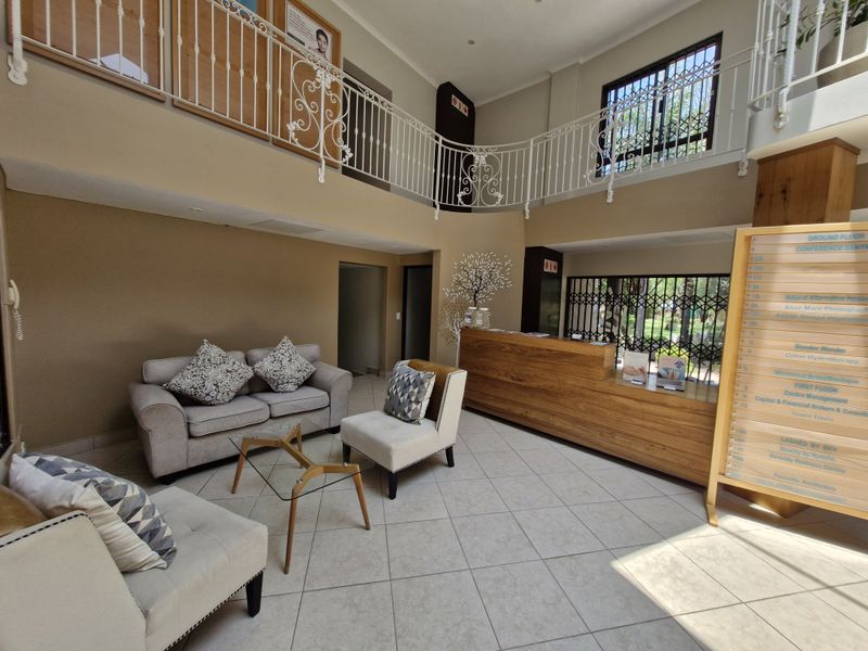 Spacious commercial reception area featuring a wooden desk, mezzanine level with decorative wrought iron railings, and a directory board for building tenants.