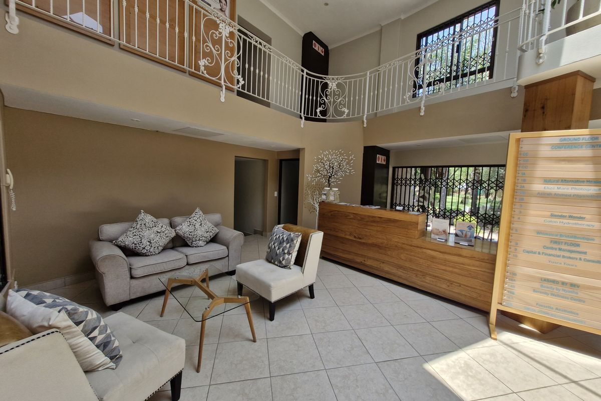Spacious commercial reception area featuring a wooden desk, mezzanine level with decorative wrought iron railings, and a directory board for building tenants.
