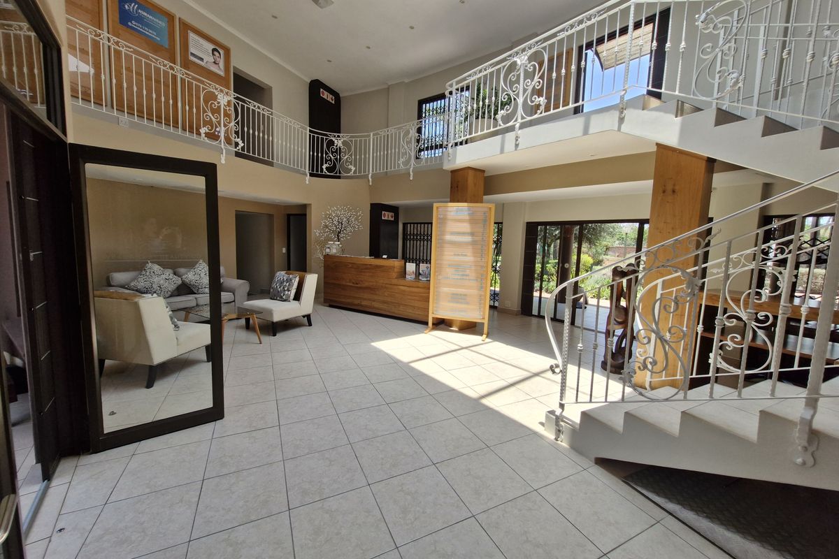 Spacious commercial entrance lobby featuring a grand staircase with wrought iron railings, tiled flooring, and a built-in reception desk.