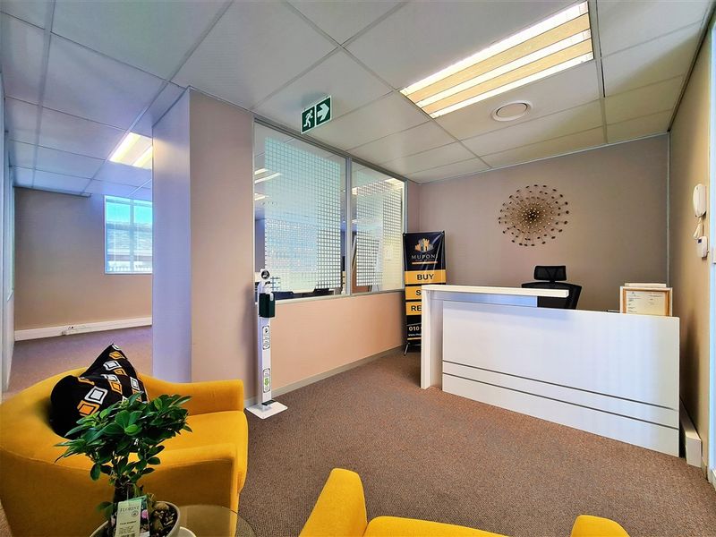 A professional office reception area featuring a built-in reception desk, glass partitioning, and a suspended ceiling with integrated lighting.