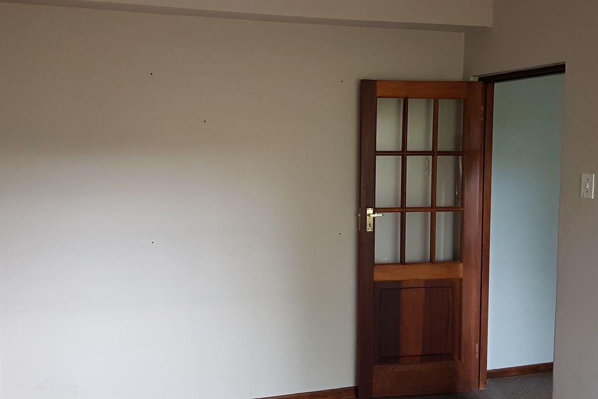 An empty office space featuring a classic timber-framed glass door and neutral wall finishes.