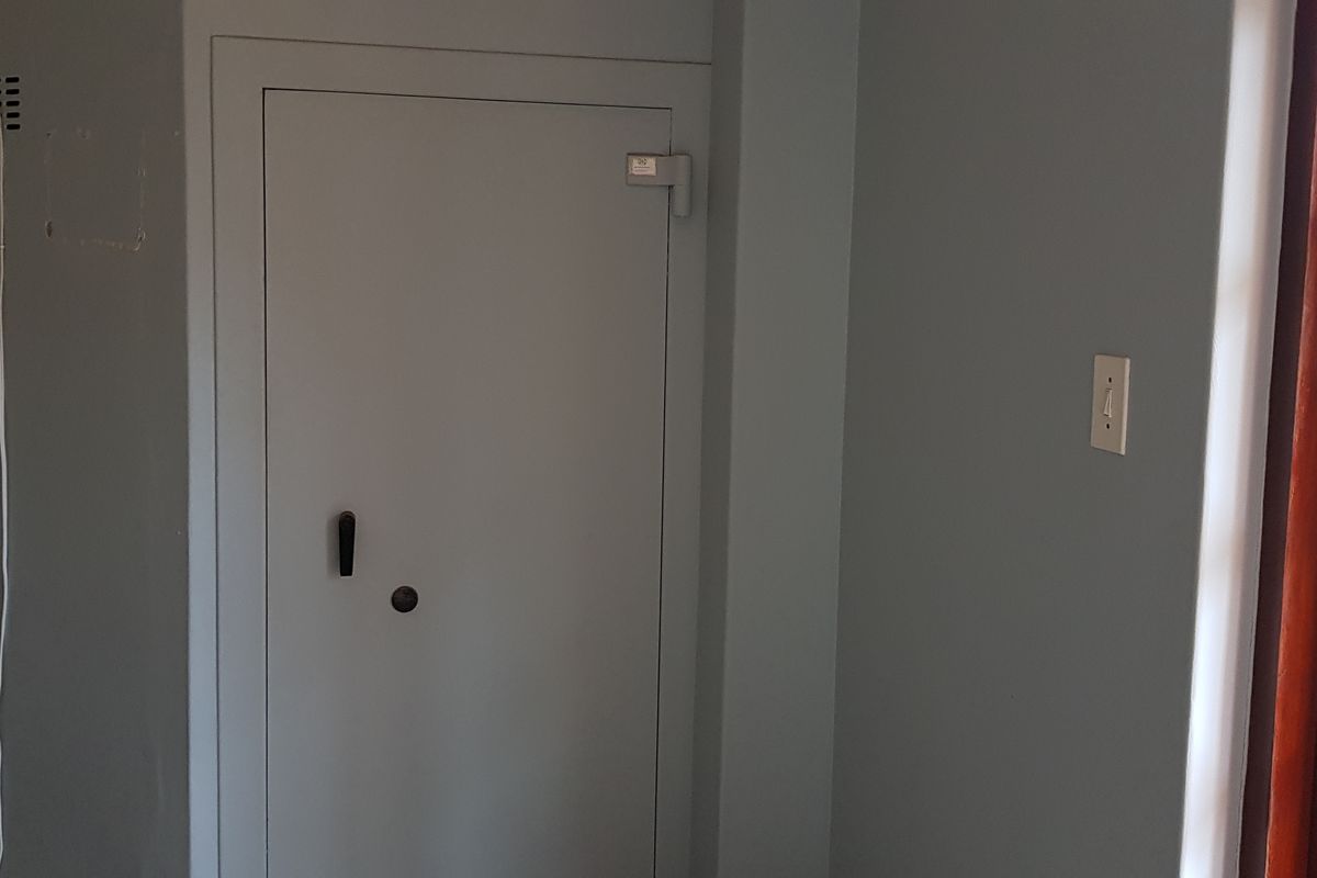 An office space featuring a secure built-in safe and a timber-framed glass door, providing a functional and secure work environment.