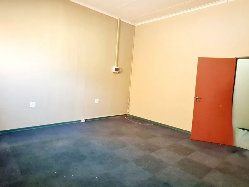 An empty office space featuring carpeted flooring, neutral wall finishes, and a single internal door, suitable for a professional workspace setup.