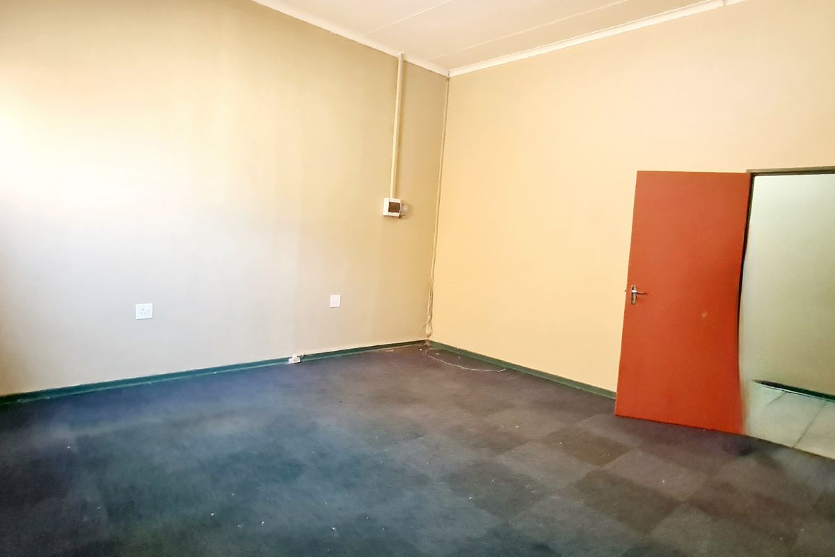 An empty office space featuring carpeted flooring, neutral wall finishes, and a single internal door, suitable for a professional workspace setup.