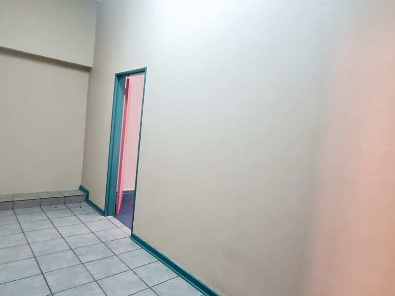 An empty office space featuring tiled flooring and a doorway leading to an adjacent room.