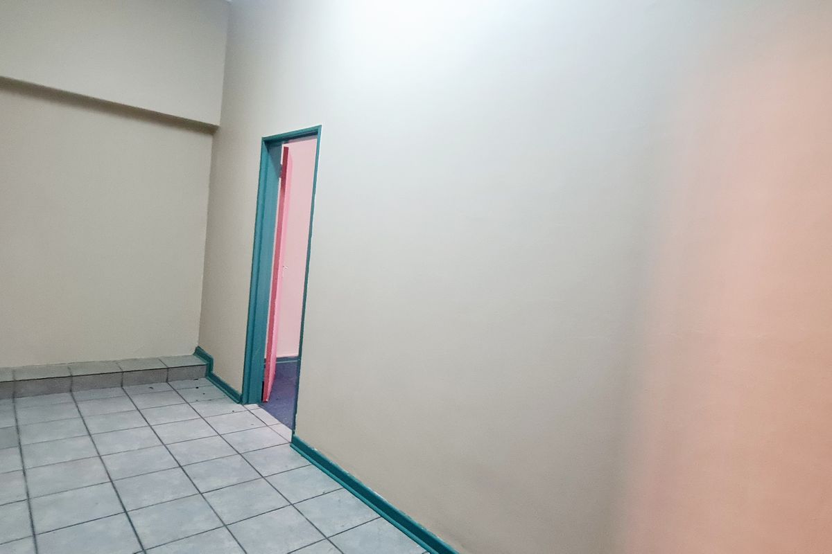 An empty office space featuring tiled flooring and a doorway leading to an adjacent room.