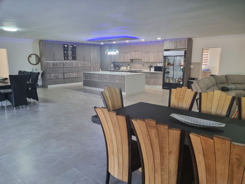 Spacious open-plan kitchen and dining area featuring modern cabinetry, a large central island, and contemporary tiled flooring throughout.