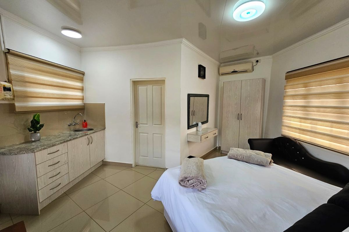 A well-maintained bedroom featuring tiled flooring, built-in cabinetry with a granite countertop, integrated sink, and split-system air conditioning.