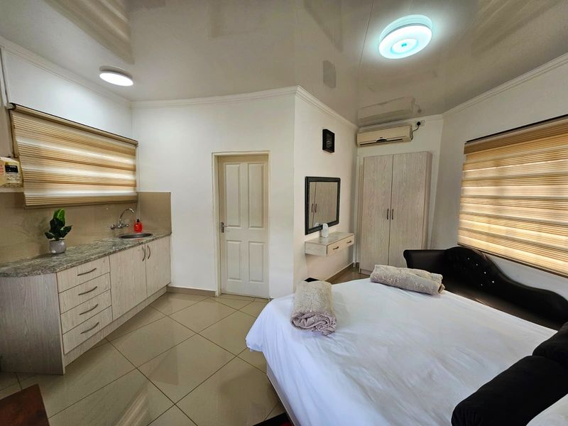 A well-maintained bedroom featuring tiled flooring, built-in cabinetry with a granite countertop, integrated sink, and split-system air conditioning.