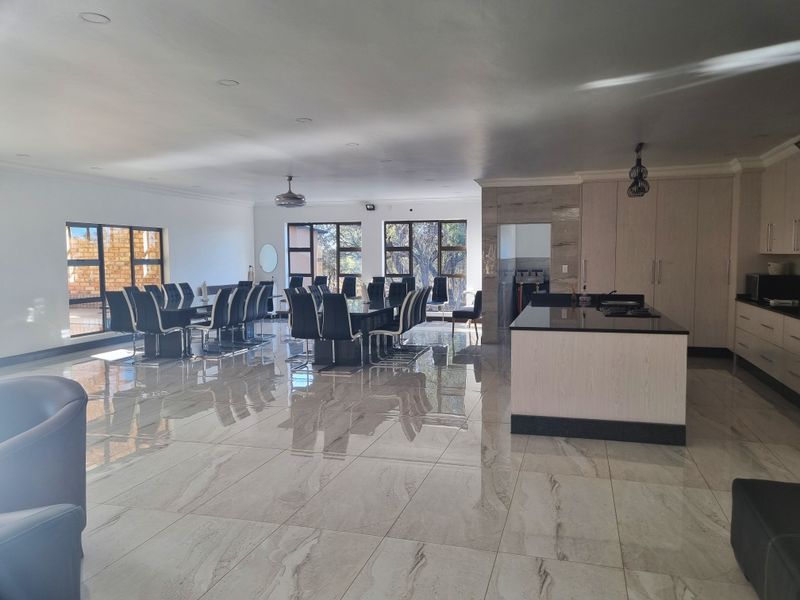 Spacious open-plan living and kitchen area featuring modern cabinetry, a central kitchen island, large windows, and polished tiled flooring throughout.