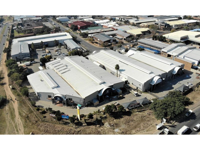 Aerial view of a large industrial warehouse complex featuring multiple units, metal roofing, and paved yard space with convenient road access.