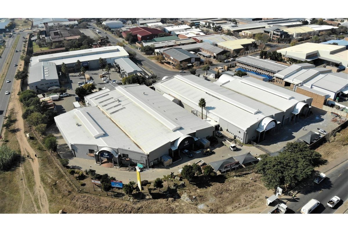 Aerial view of a large industrial warehouse complex featuring multiple units, metal roofing, and paved yard space with convenient road access.