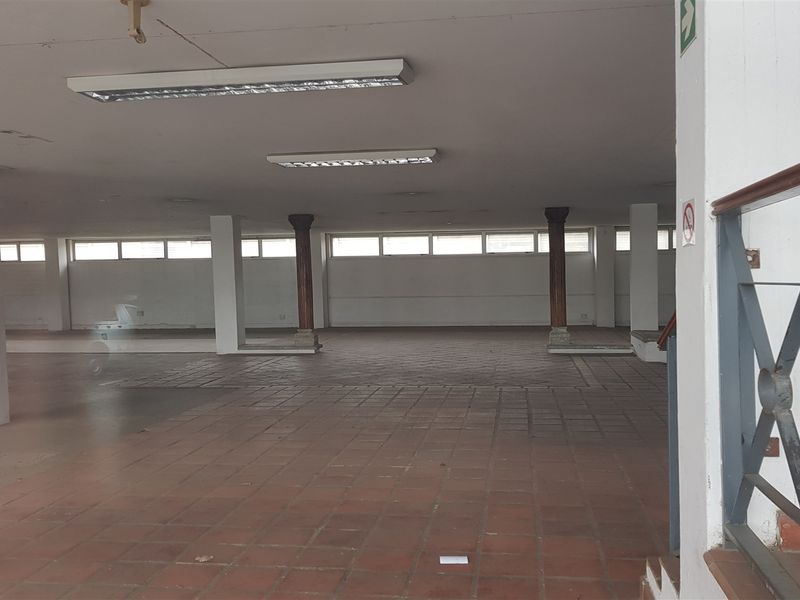 Large open-plan industrial utility space featuring terracotta tile flooring, structural columns, and overhead fluorescent lighting.