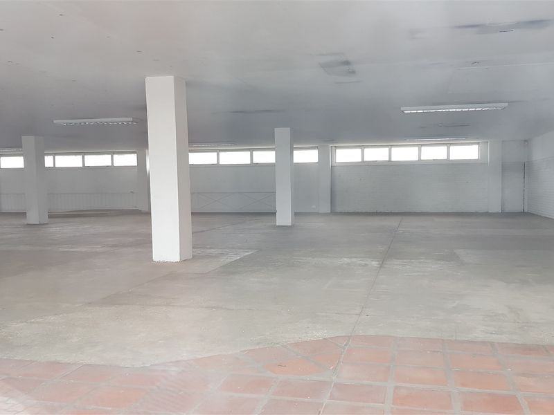 Expansive open-plan industrial utility space featuring concrete flooring, structural support columns, and high-level clerestory windows providing natural light.