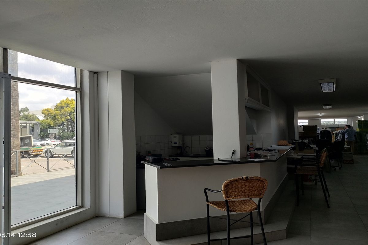 A functional industrial kitchen area featuring a built-in counter, tiled flooring, and large windows providing natural light.