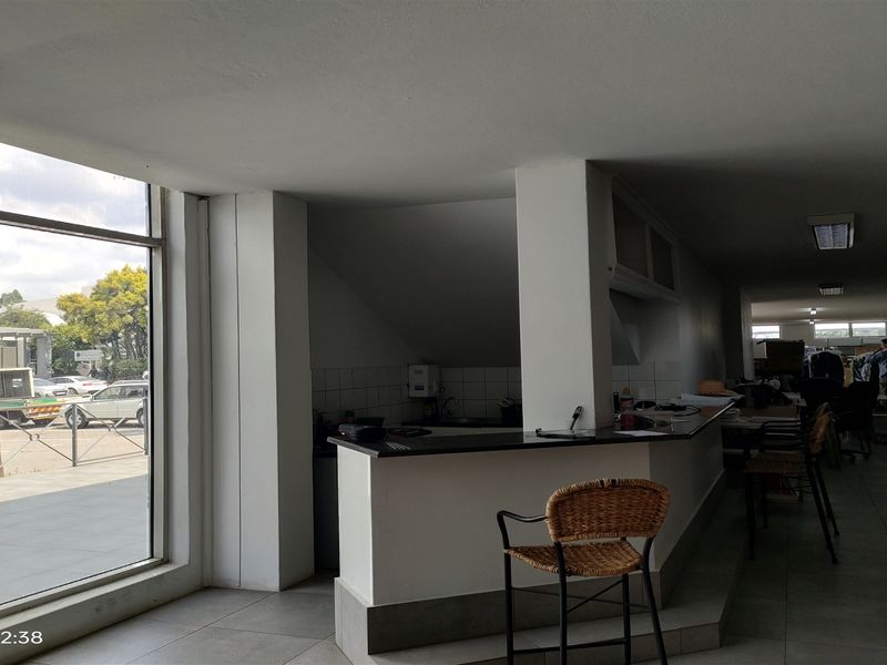 A functional industrial kitchen area featuring a built-in counter, tiled flooring, and large windows providing natural light.