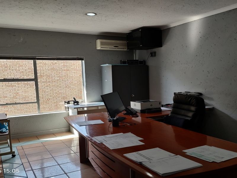 A functional office space featuring tiled flooring, recessed lighting, and an integrated air conditioning unit, suitable for professional use.