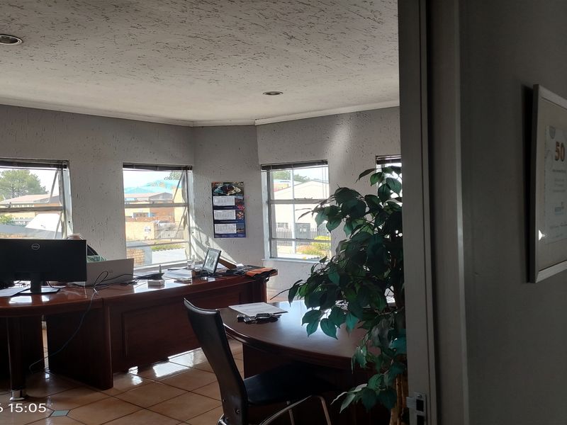 A functional office space featuring tiled flooring, recessed lighting, and multiple windows providing natural light.