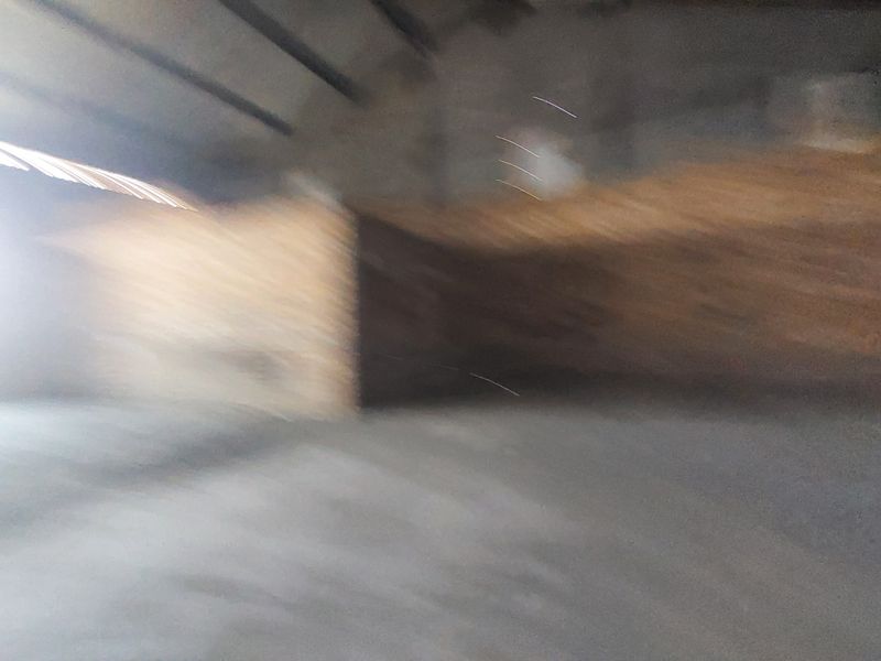 A large, empty industrial utility space featuring concrete flooring and exposed structural beams, currently captured with significant motion blur.