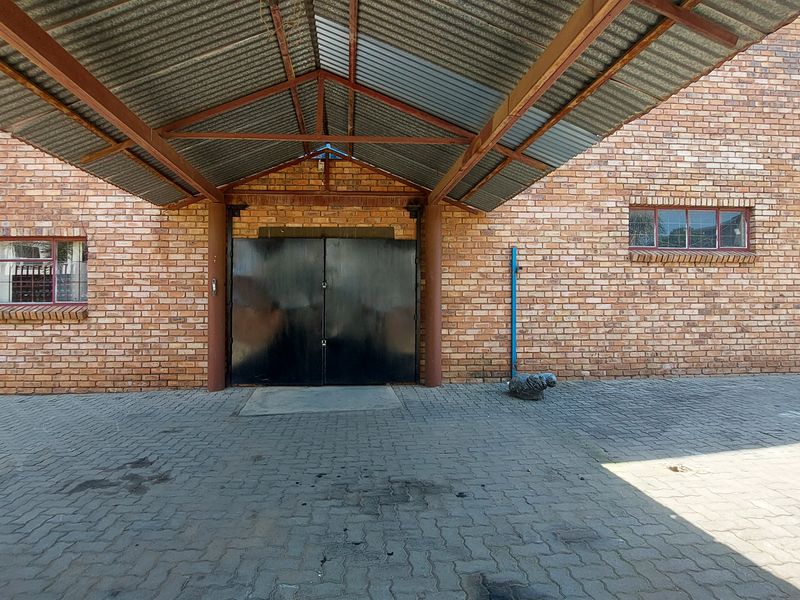 Industrial property entrance featuring a covered canopy, double steel doors, and a durable face brick facade with paved driveway access.