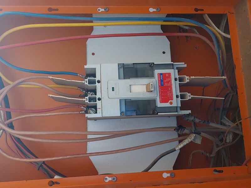 Industrial electrical distribution board featuring a 150A hydraulic magnetic circuit breaker with exposed wiring connections within a metal enclosure.