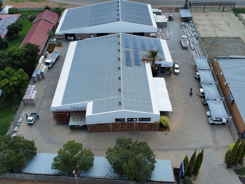 Aerial view of an industrial property featuring multiple warehouse buildings with solar panels, paved yard space, and covered parking areas.