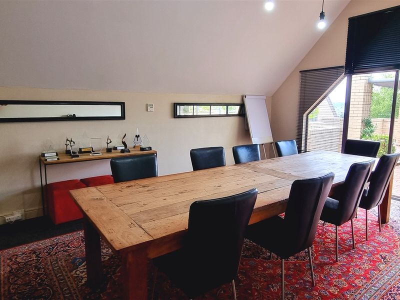Spacious office area featuring vaulted ceilings, recessed lighting, and large glass sliding doors providing direct access to an outdoor patio space.