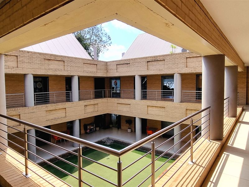 A view of the office complex courtyard featuring a two-story brick structure with wrap-around balconies and a central green space.