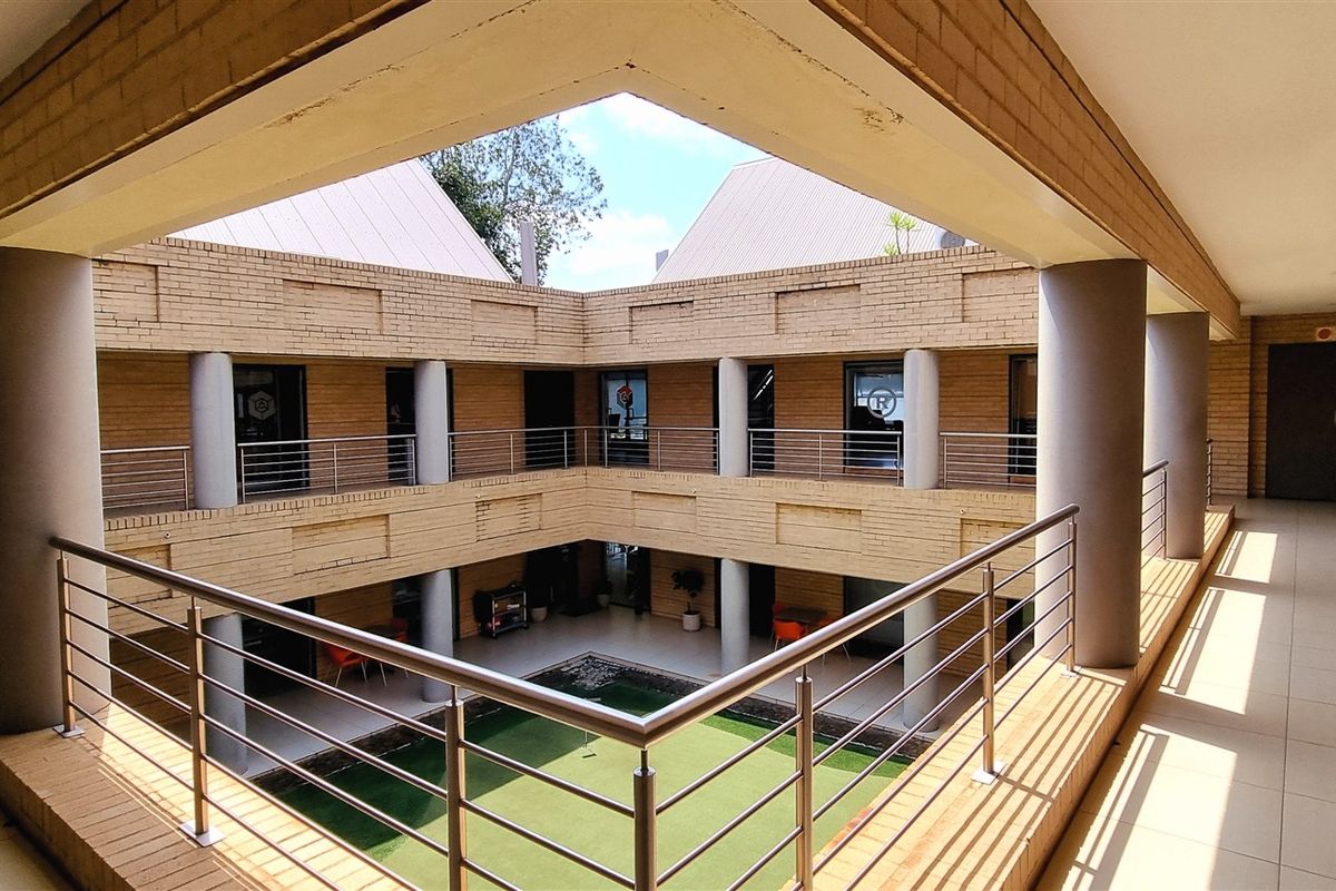 A view of the office complex courtyard featuring a two-story brick structure with wrap-around balconies and a central green space.