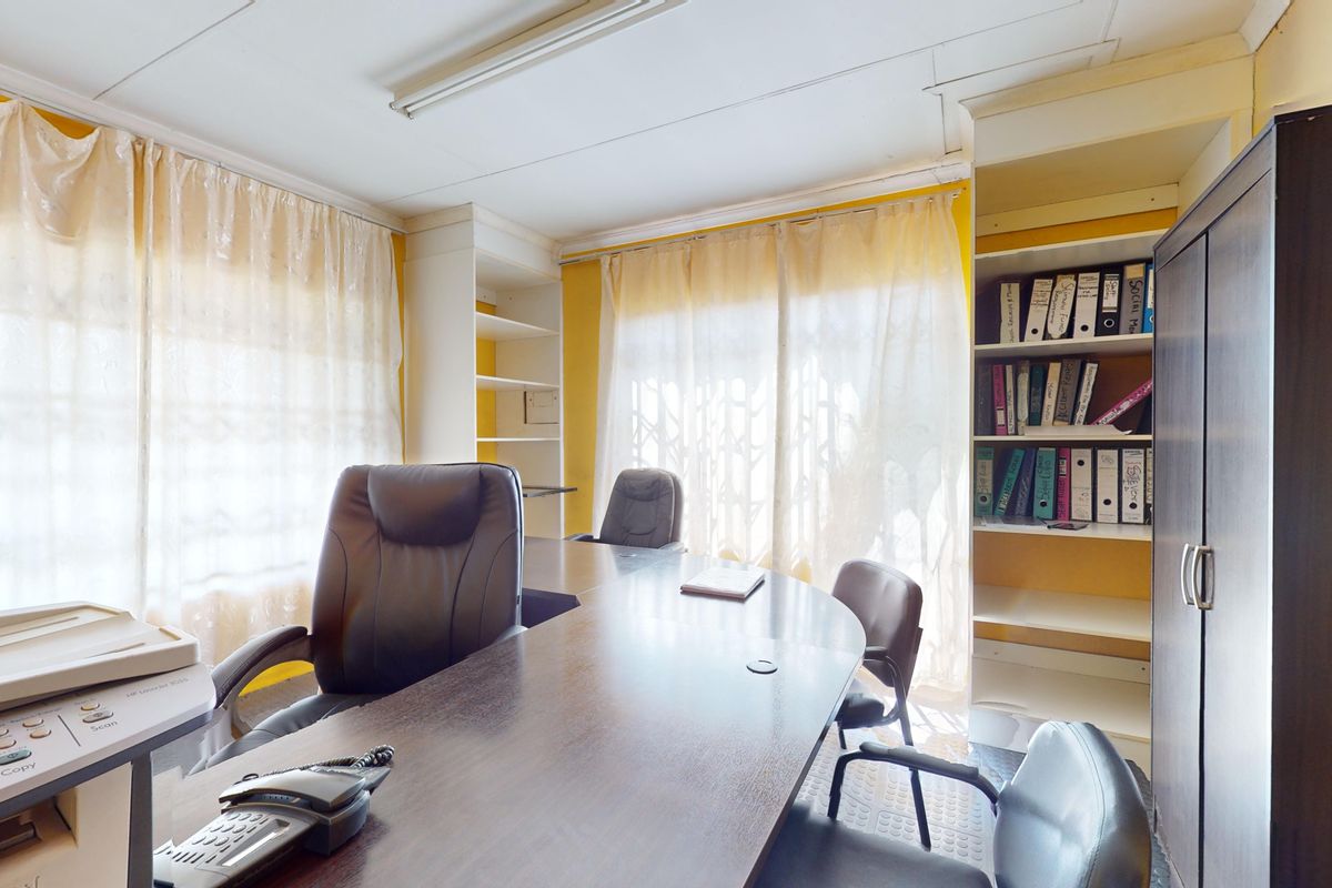 A functional office space featuring built-in shelving units and large windows with natural light, suitable for a professional work environment.